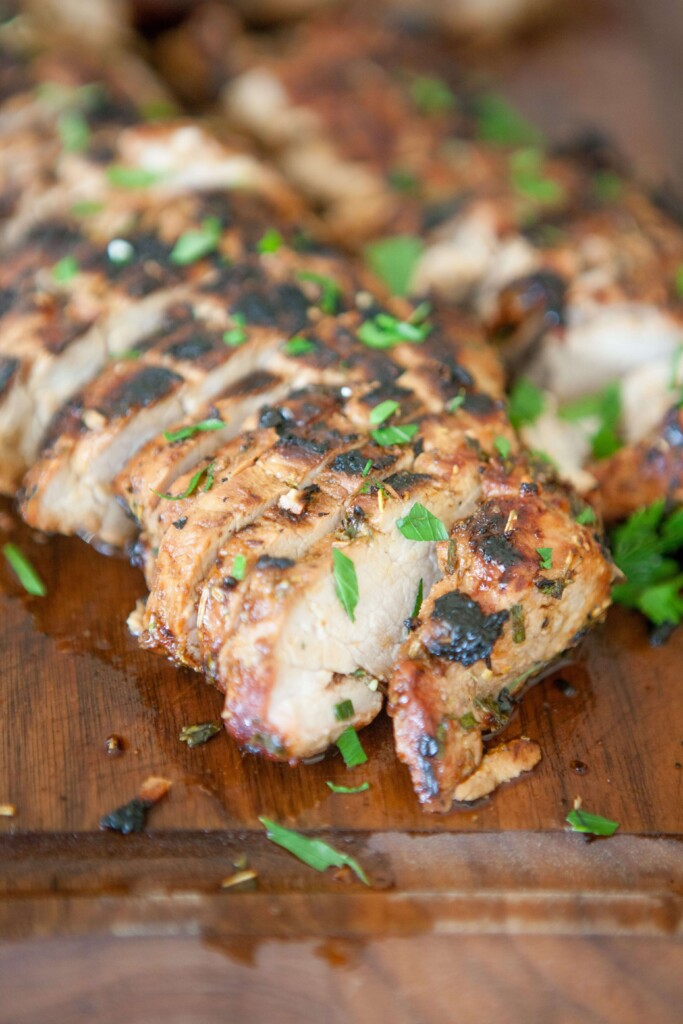 Balsamic and herb pork tenderloin sliced and garnished with fresh herbs.