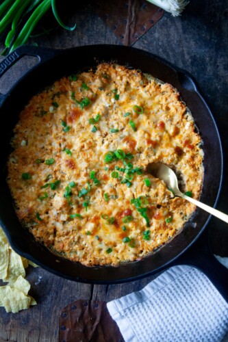 Buffalo chicken dip baked in cast iron skillet with spoon.