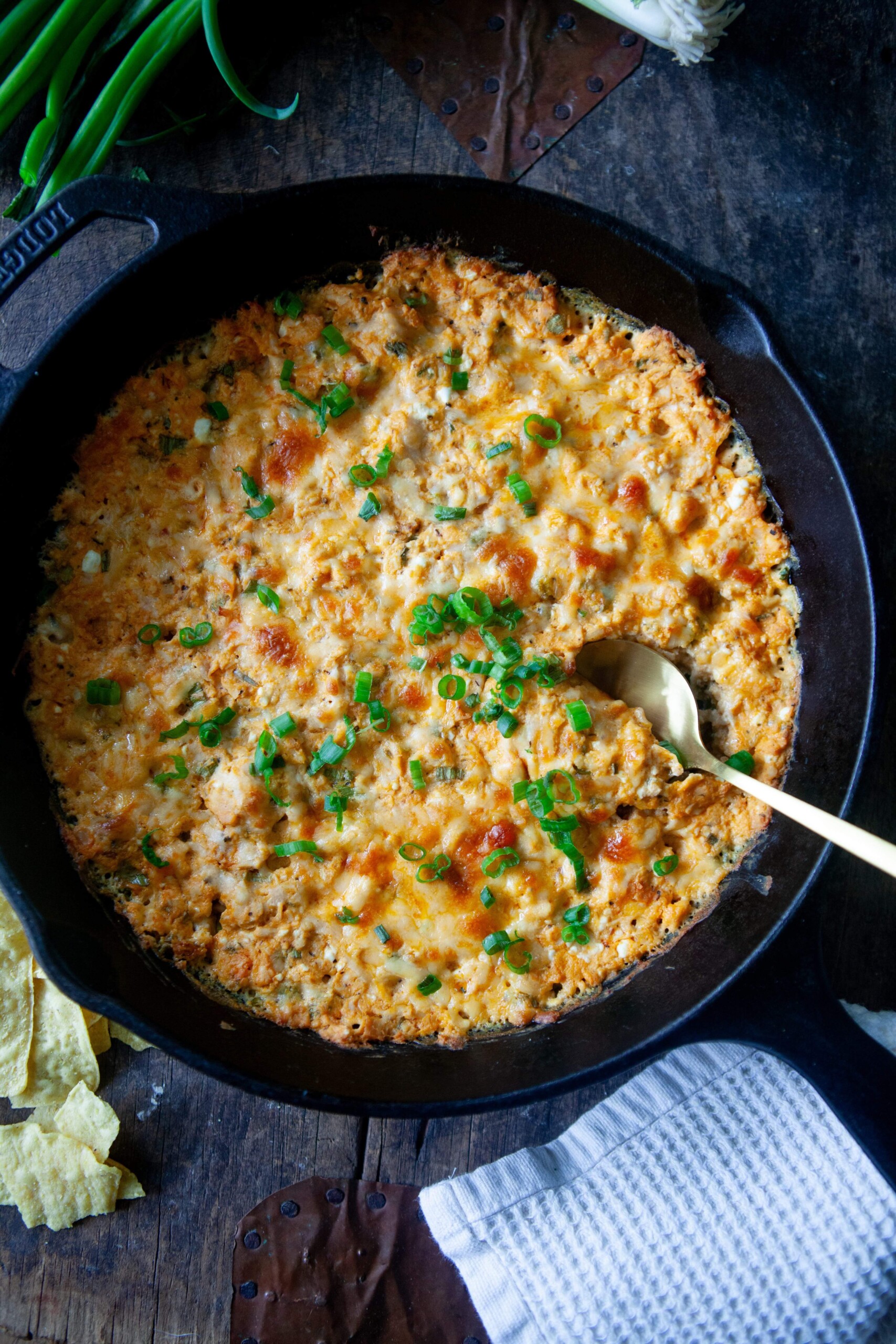 Buffalo chicken dip baked in cast iron skillet with spoon.