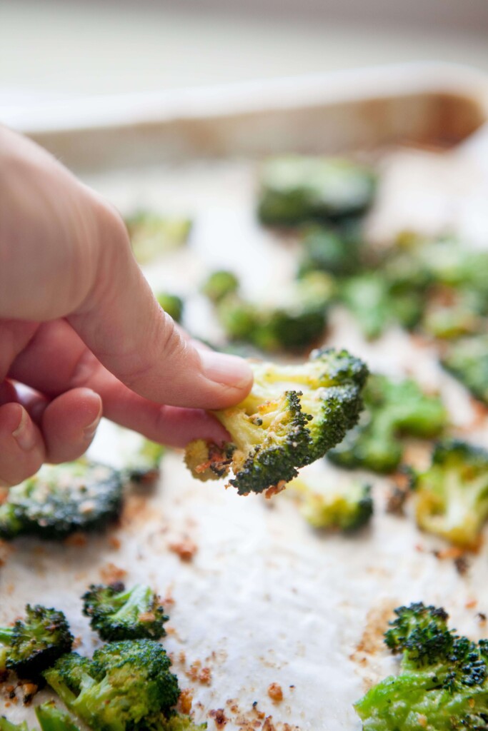 Hand holding roasted broccoli floret.