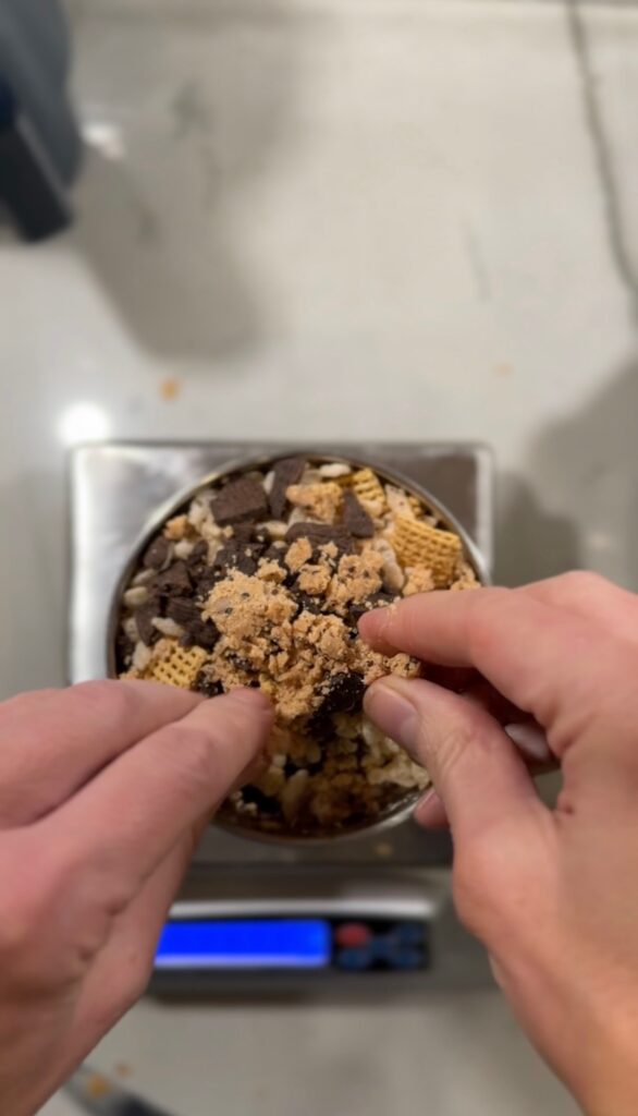 Sprinkling toppings on top of chocolate peppermint protein shake in metal tumbler.