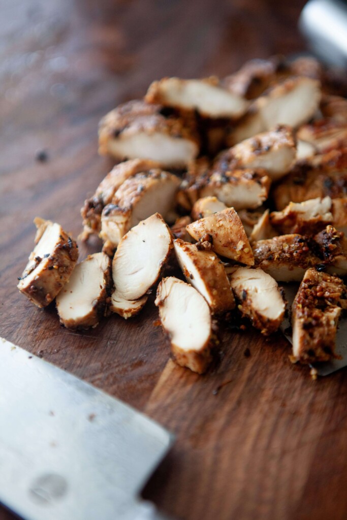 Balsamic, dijon, garlic chicken tenders cut on wood cutting board.