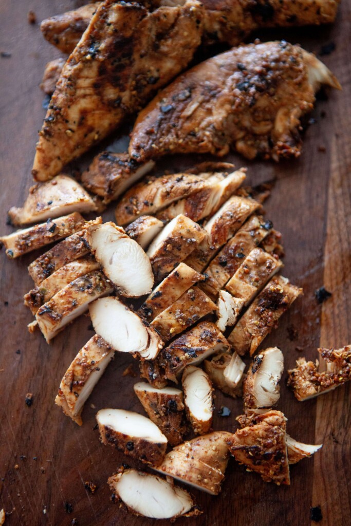 Balsamic, dijon, garlic chicken tenders chopped up on wood cutting board.