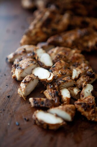 Balsamic, dijon, garlic chicken tenders cut on wooden cutting board.