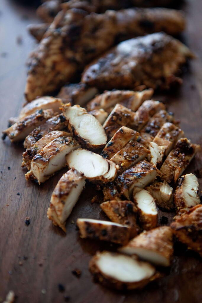 Grilled balsamic, dijon, garlic chicken tenders cut on wood cutting board.