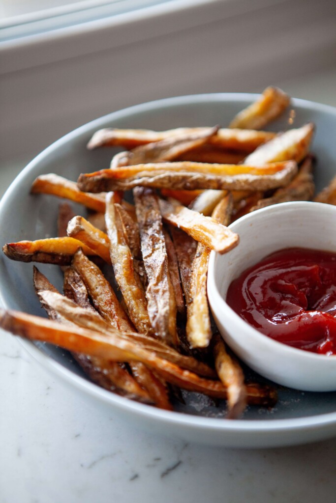 Healthy french fries in white bowl with side of ketchup.