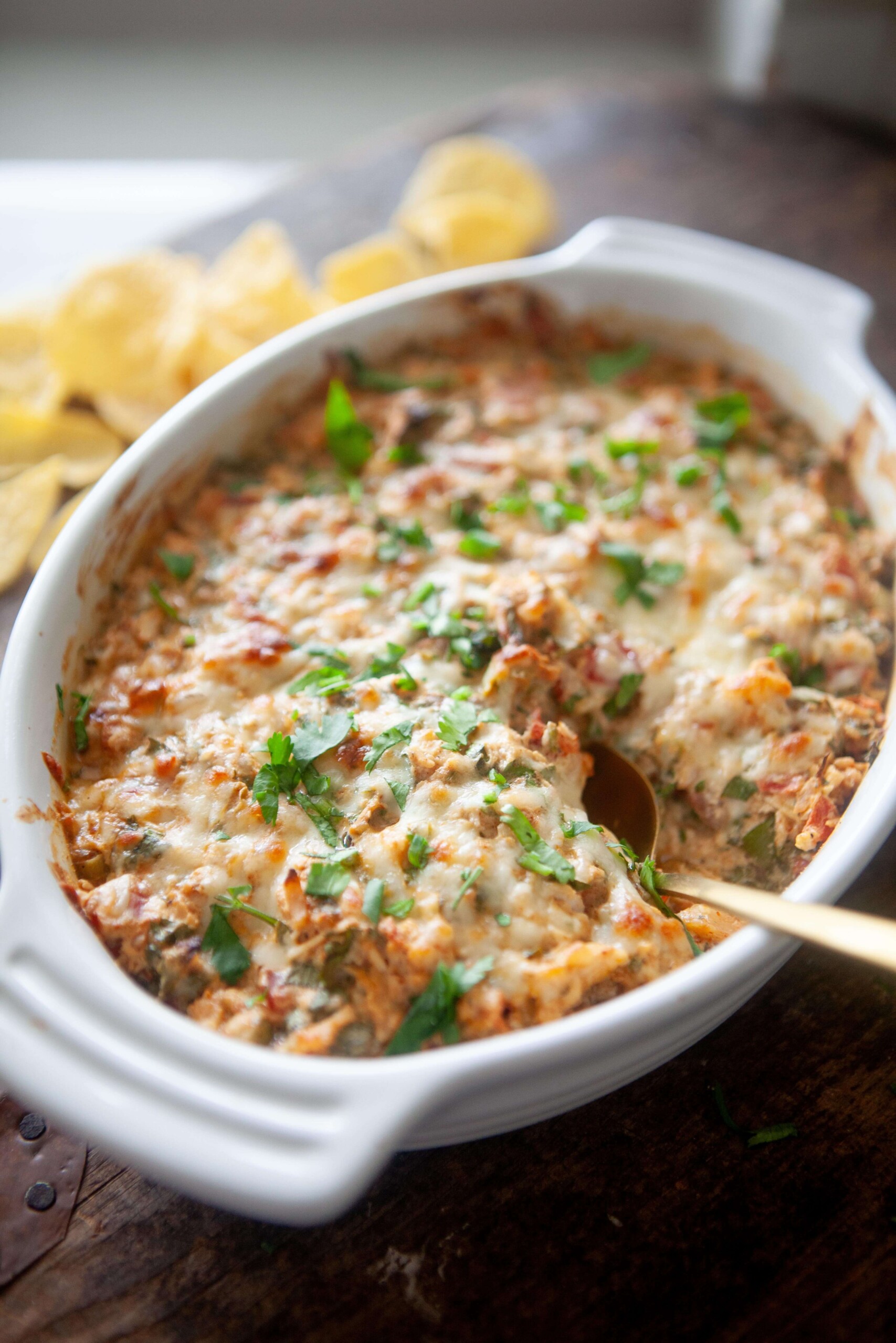 Creamy rotel chicken bake cooked in white baking dish with gold spoon.