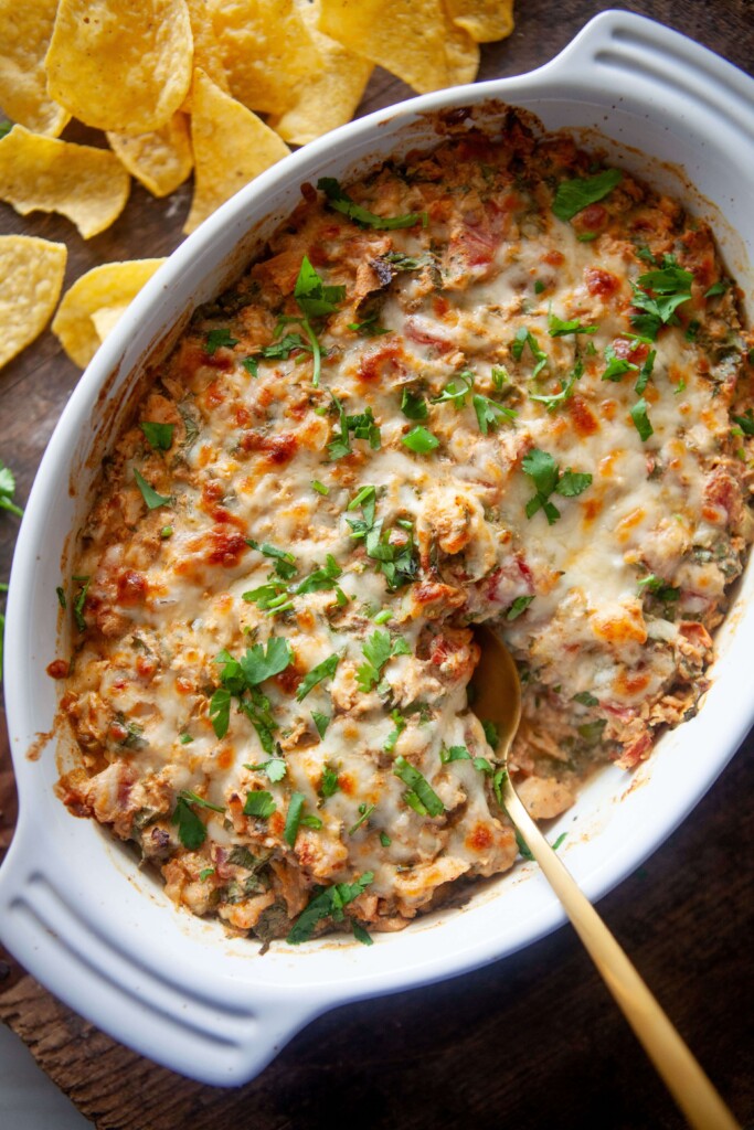 Gold spoon dipping into creamy rotel chicken bake.