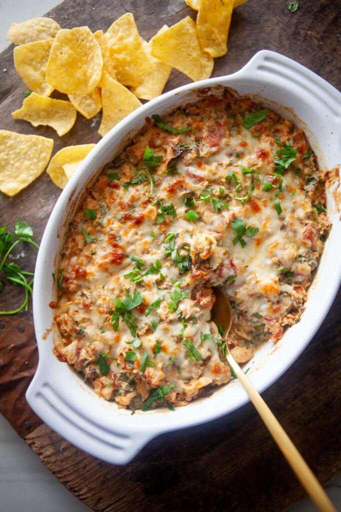 Creamy rotel chicken bake cooked in white baking dish with gold spoon.