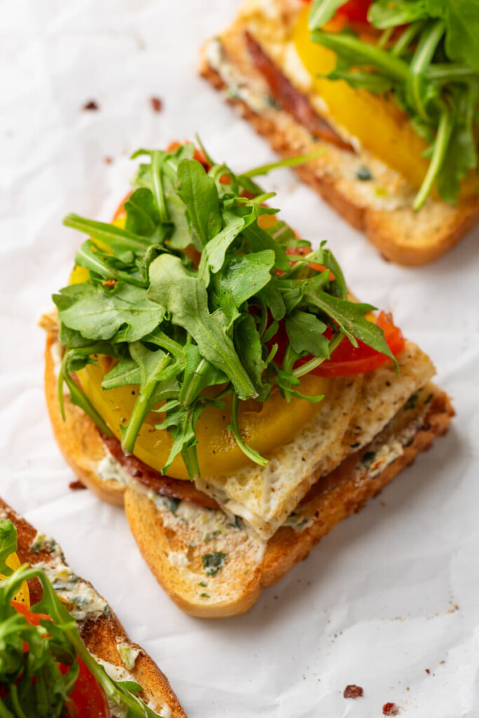Tomato egg white toast topped with arugula and cut in half.