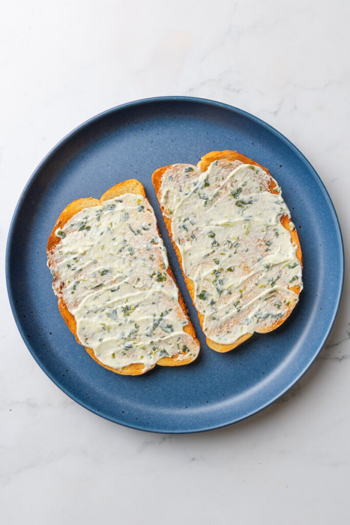 Basil yogurt spread on two pieces of sourdough toast.