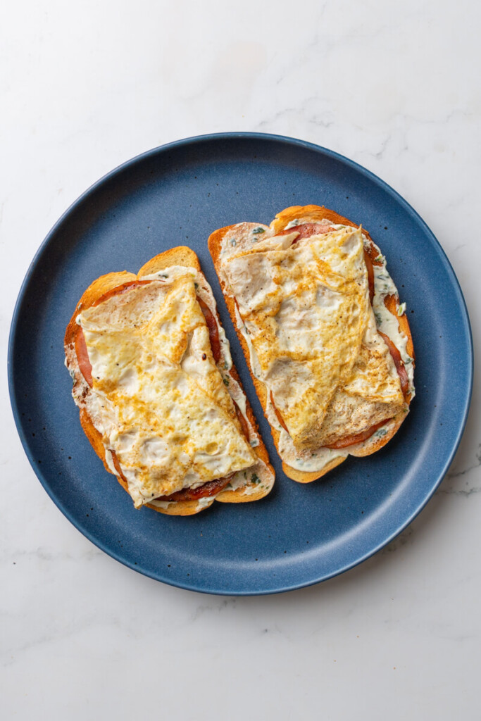 Two pieces of sourdough topped with basil yogurt, ham and egg whites.