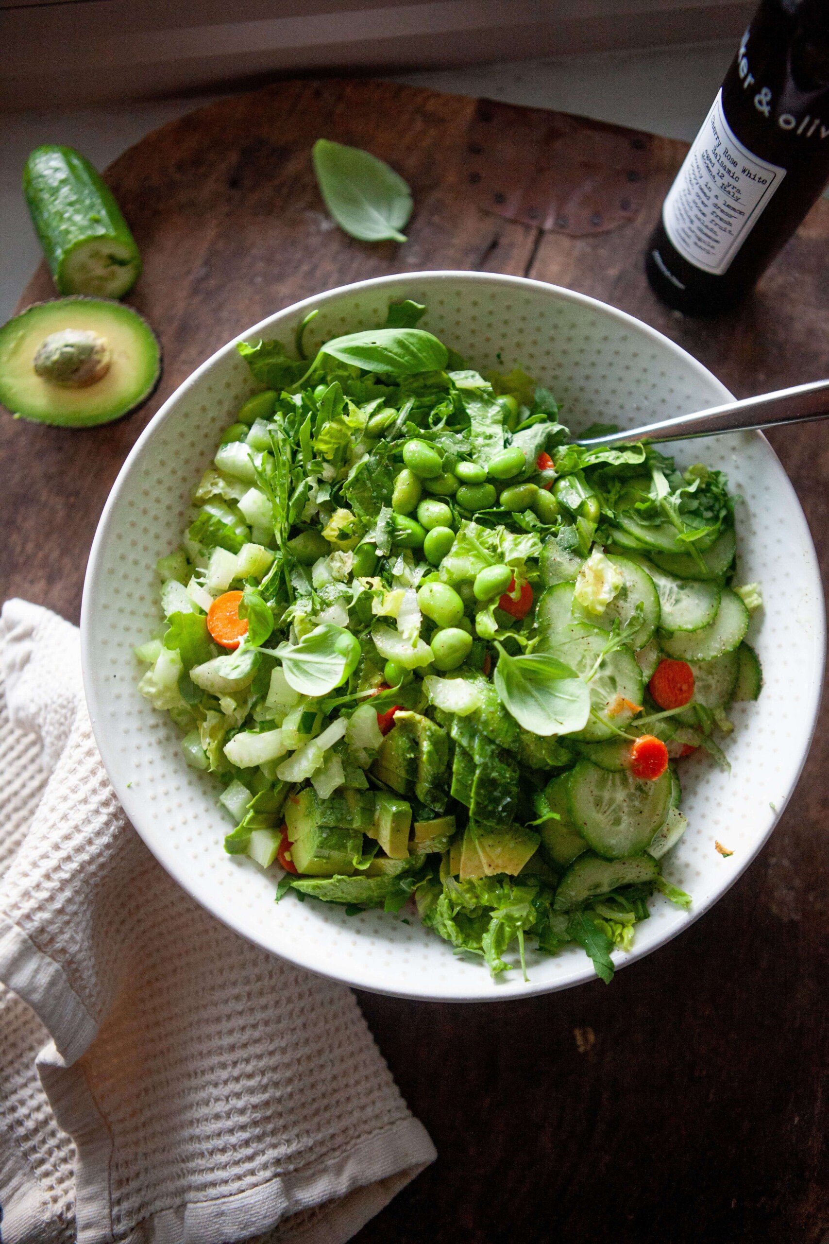 Ingredients for house salad mixed together and served in a bowl with fork on the side.
