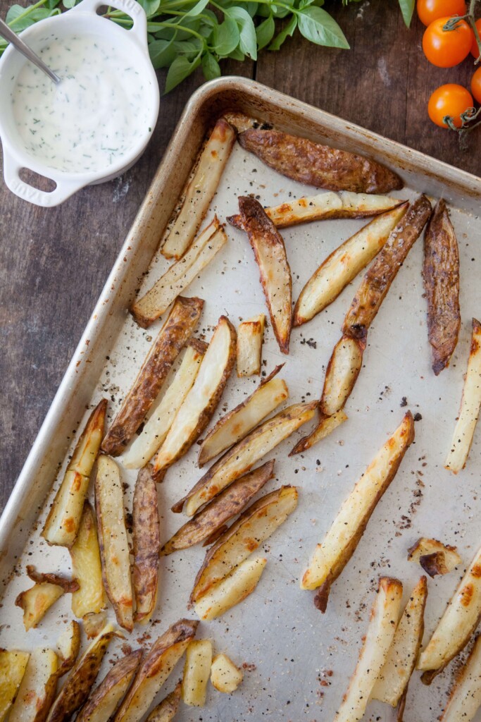 Oven roasted fries baked on baking sheet and sprinkled with seasonings.
