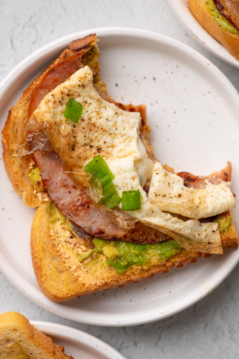 Chipotle egg white toast on a plate with two bites taken out of it.