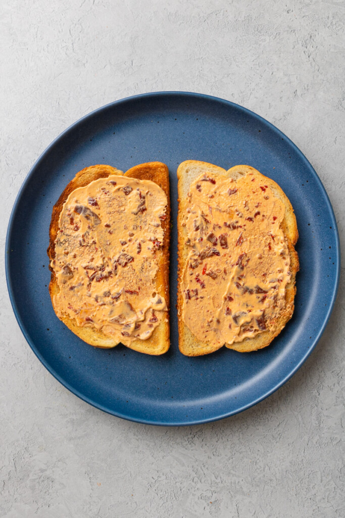 Two pieces of toasted bread topped with chipotle cream.