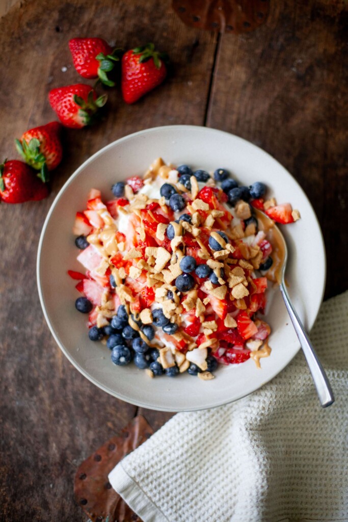 Chocolate protein breakfast bar in a bowl with whipped cream, fresh berries and a drizzle of nut butter as toppings.