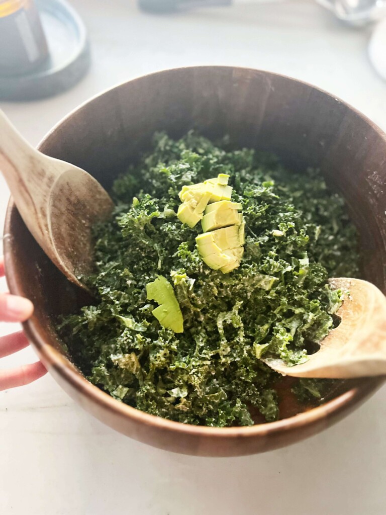 Kale caesar salad tossed in a large wooden bowl.