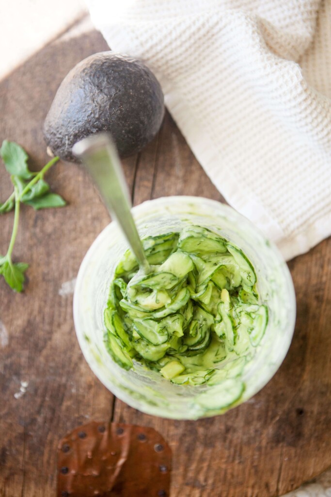 Creamy cucumber salad mixed together in large plastic container.
