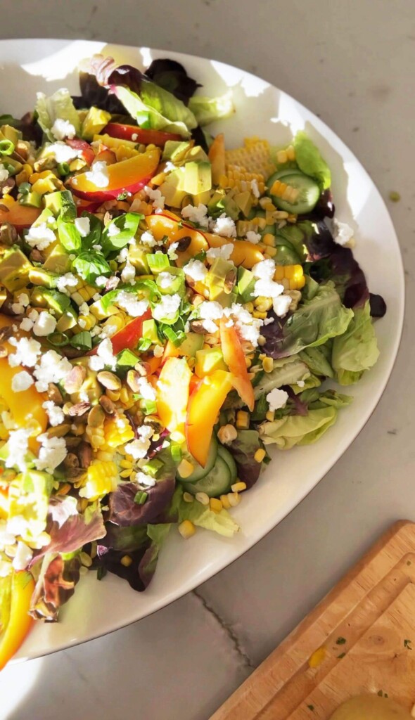 Summer peach, corn, and goat cheese salad in a bowl.