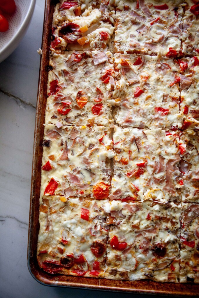 Sheet pan roasted veggie egg bake cooked and sliced on large sheet pan.