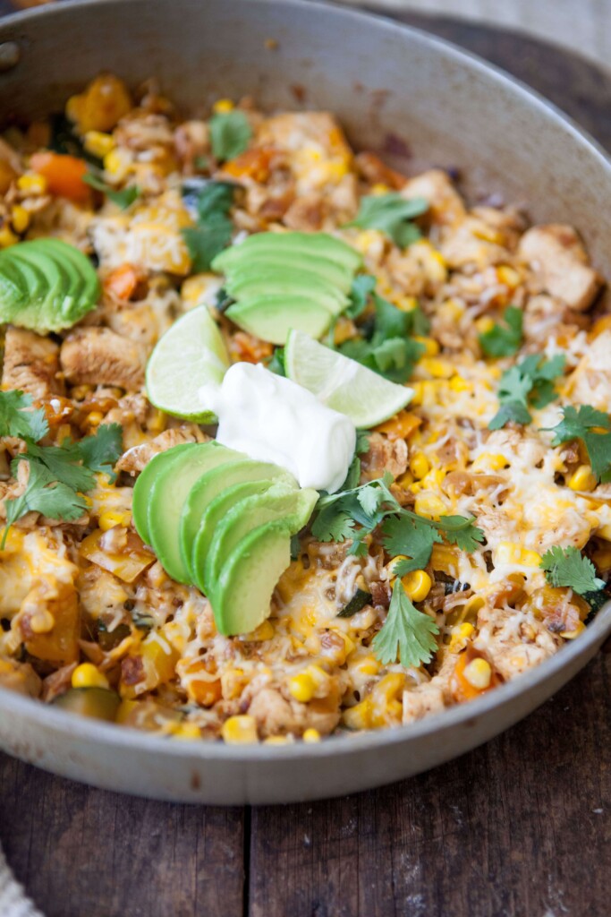 Zucchini, corn and chicken skillet topped with fresh lime, avocado and sour cream in skillet.
